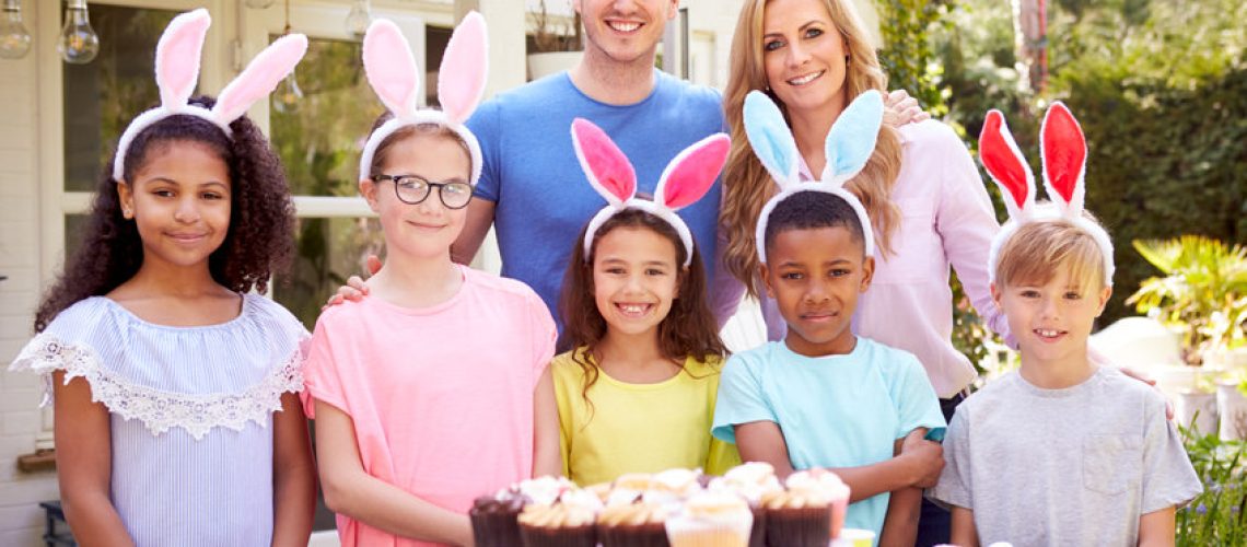 Portrait Of Parents With Children Wearing Bunny Ears Enjoying Outdoor Easter Party In Garden At Home